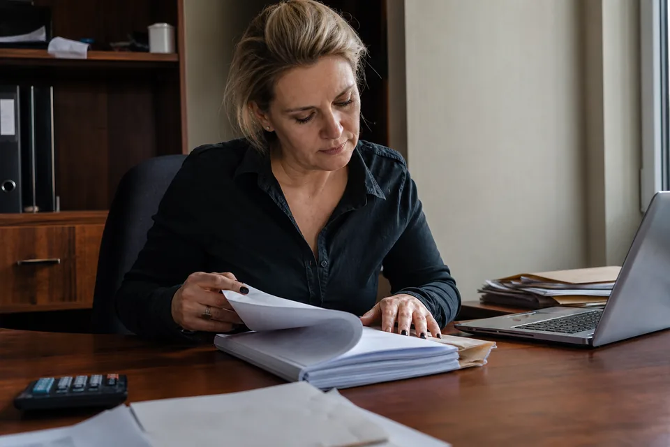 Właścicielka firmy przegląda w biurze teczkę z wyrokiem i dokumentami sprawy