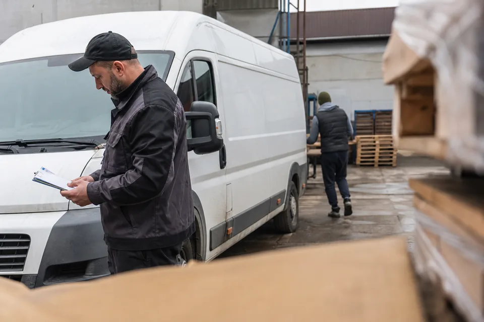 Kierowca przy samochodzie dostawczym na placu firmy
