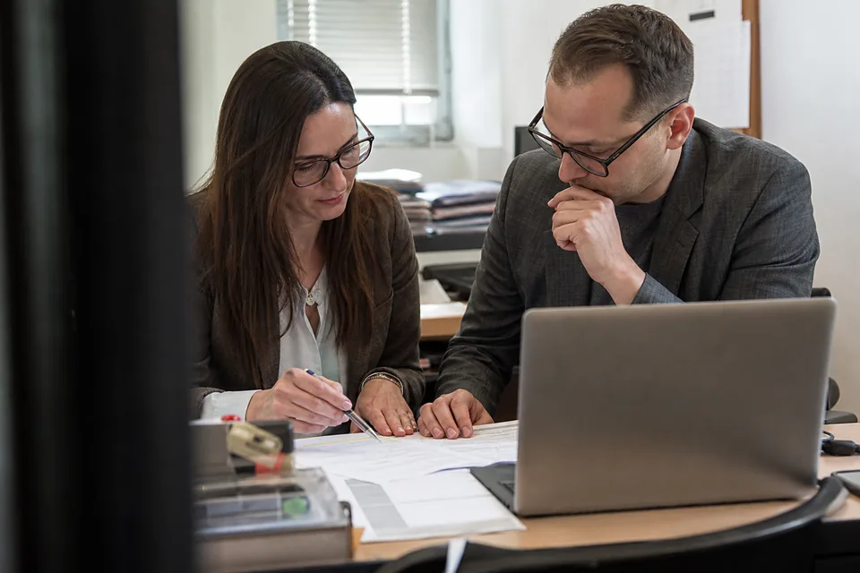 Zespół finansów przegląda listę należności na wydruku i laptopie
