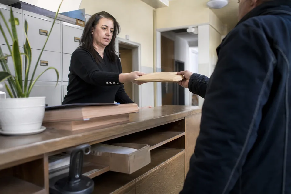 Pracowniczka biura przekazuje kurierowi kopertę z wnioskiem do kancelarii komorniczej